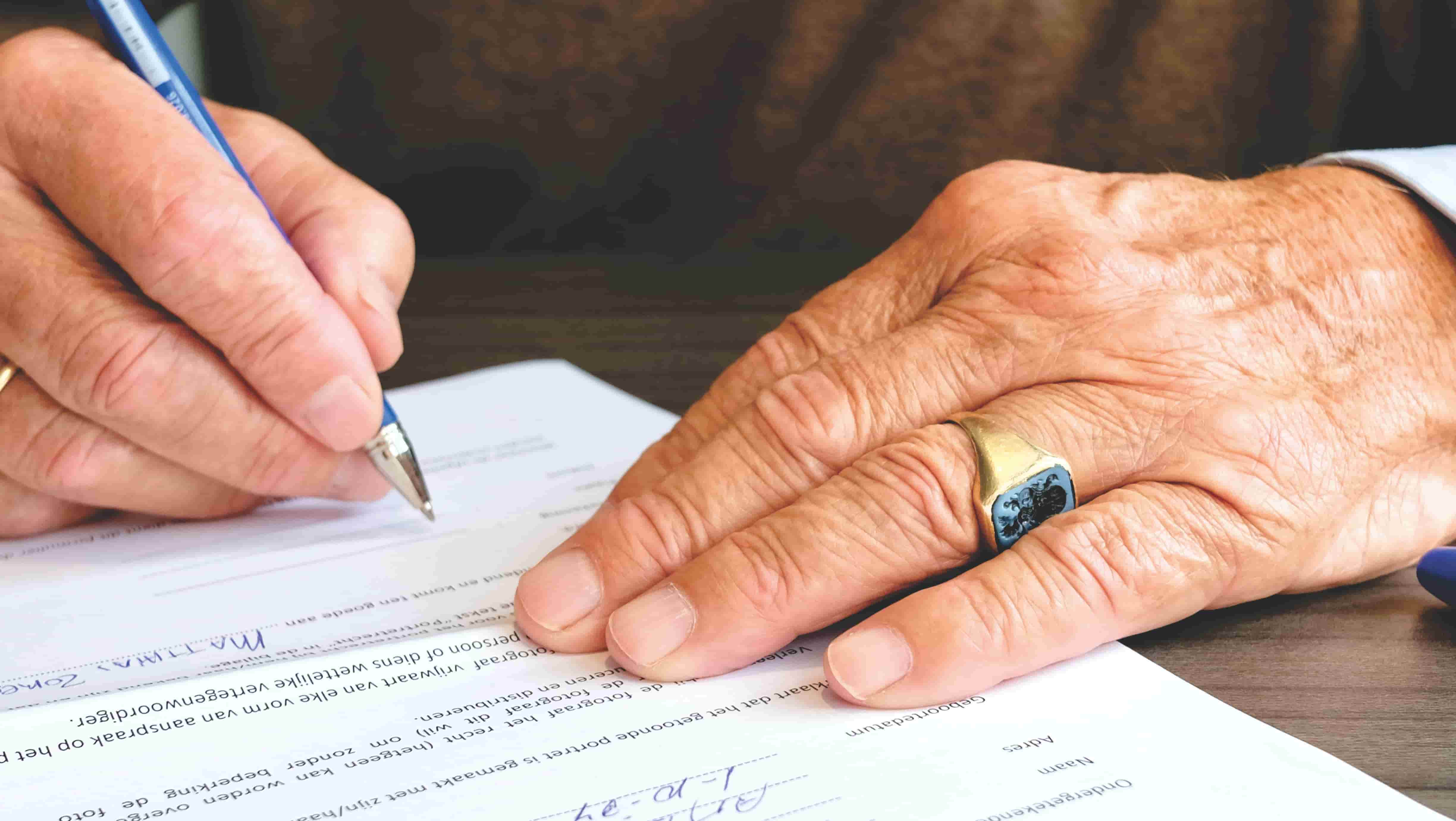 Mano con anillo firmando un documento oficial.